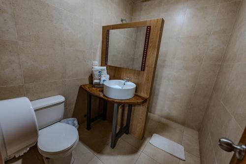 a bathroom with a sink and a toilet and a mirror at Hotel Nantu Hostería in Puerto López