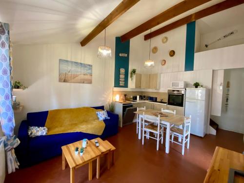 un salon avec un canapé bleu et une cuisine dans l'établissement Maison au calme dans la pinède, à Lacanau