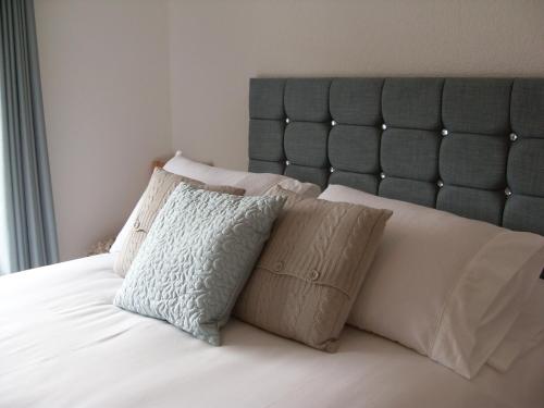 a neatly made bed with white sheets and pillows at Dol aur Bed and Breakfast in Harlech