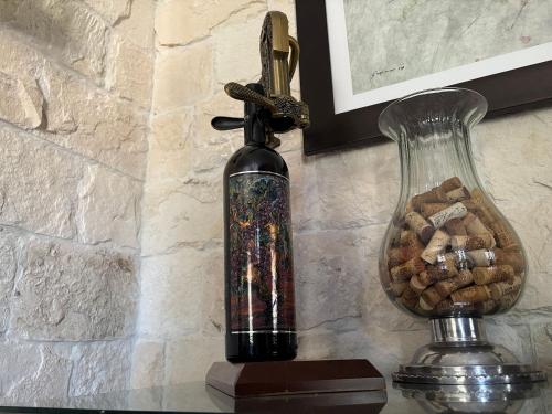a bottle of wine on a table next to a vase at Carrara: Armonía, Lujo y Confort en Val’Quirico in Santeagueda
