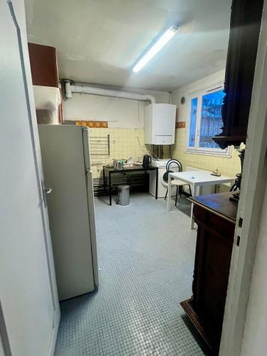 une cuisine avec un réfrigérateur et une table à l'intérieur dans l'établissement Villa Jasmin, à Bobigny