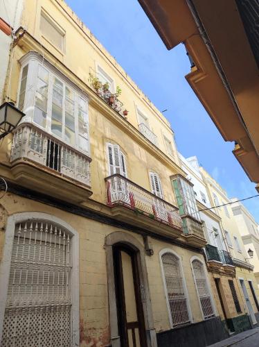 a building with windows and balconies on a street at Old Merchant's Home in Cádiz