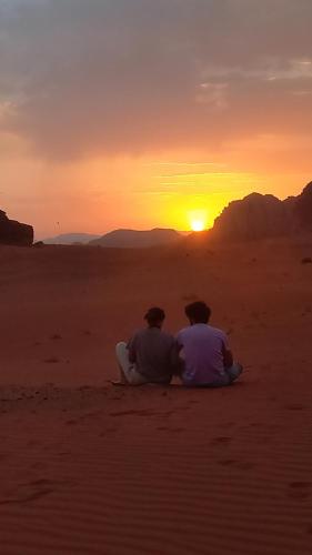 two people sitting in the desert watching the sunset at Lowrance luxury camp in Wadi Rum