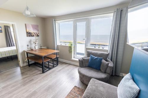 a living room with a table and chairs and windows at SEA VIEW - First Floor 3 bed apartment looking over Bridlington North Beach in Bridlington
