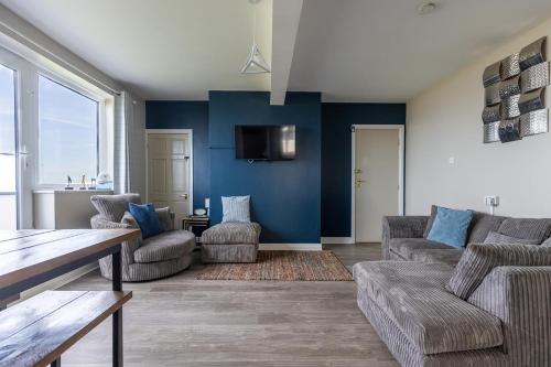a living room with blue walls and a couch and chairs at SEA VIEW - First Floor 3 bed apartment looking over Bridlington North Beach in Bridlington