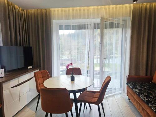 a living room with a table and chairs and a large window at Słoneczny Brzeg - Apartamenty w Pieninach in Krościenko