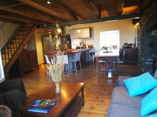 a living room with a couch and a table and a kitchen at Ferme traditionnelle in La Jarriage