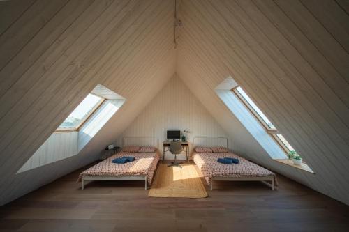 a attic room with two beds and two windows at Svencelė K-17 in Svencelė