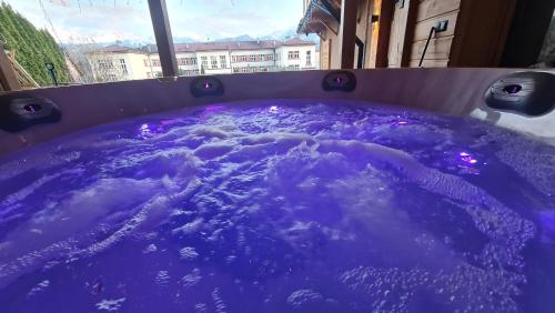 a purple bath tub with purple lights in it at Villa Fortuna - Regionalne apartamenty & SPA - Sauna, Grill, Jacuzzi z widokiem na Tatry in Zakopane