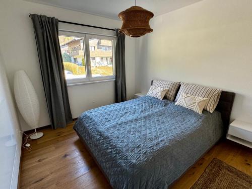 a bedroom with a bed with a blue comforter and a window at Bergpanorama in Sankt Gilgen