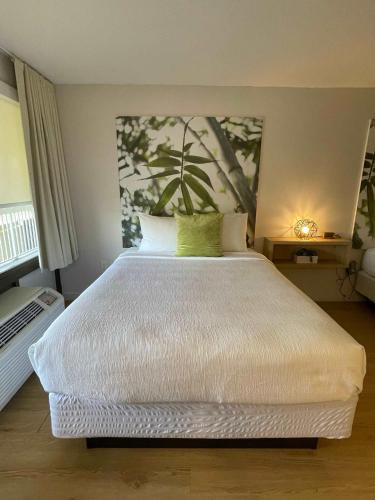a bedroom with a white bed with a painting on the wall at Newly renovated room in cozy hotel near Disney 2 in Kissimmee