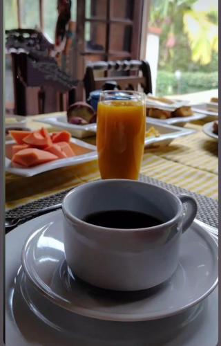 a cup of orange juice sitting next to a bowl of coffee at Chalé do lago Ladeira de Pedra in Salesópolis