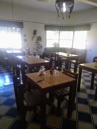 a restaurant with wooden tables and chairs and windows at Hosteria Calamuchita in Villa del Dique