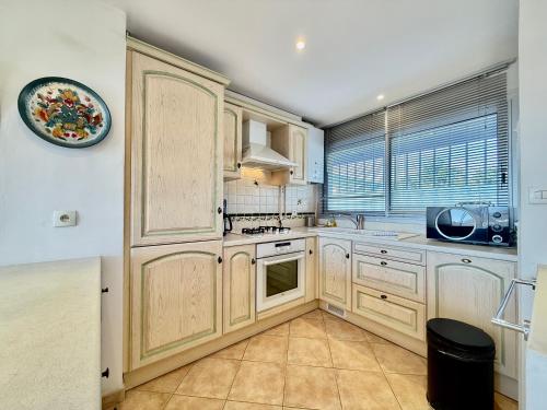 une grande cuisine avec des placards en bois et une fenêtre dans l'établissement Style Exotique - Vue Mer Panoramique, à Carqueiranne