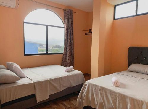 a room with two beds and a window at Family Apartment in San Cristóbal with 2 Bedrooms, 4 Beds, Living Room, Dining Area, Kitchen, Satellite WiFi and 1 Bathroom with Hot Water - CoralBay - Galápagos Home in Puerto Baquerizo Moreno