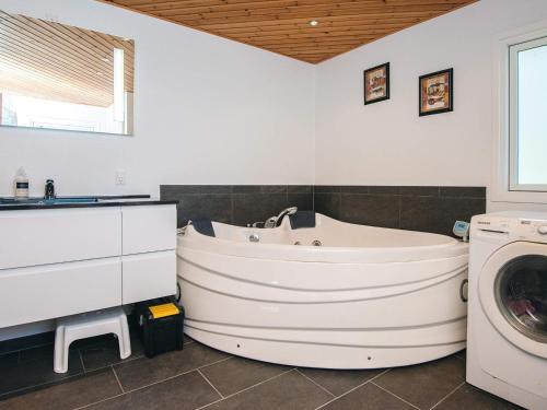 a bathroom with a white tub and a washing machine at Panoramic Fjord Retreat with Spa Bath in Øster Assels
