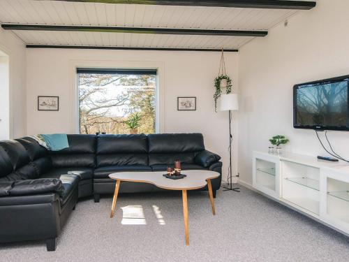 a living room with a black leather couch and a table at 5 person holiday home in Snedsted in Snedsted