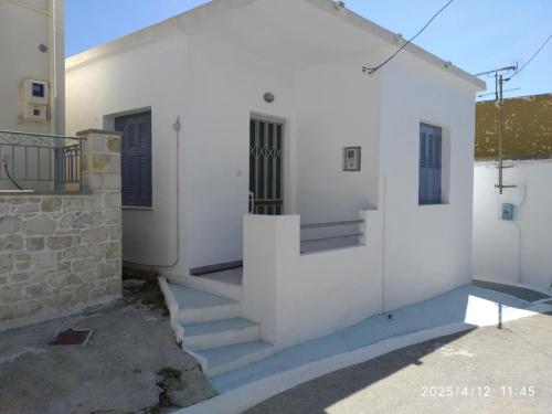 a white building with stairs and a door at Oneiro Paralio Astros Nisi in Paralion astros