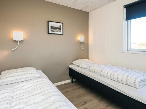 two beds in a room with two lights on the wall at Luxury Retreat with Pool - By Traum Ferienwohnungen in Harboør