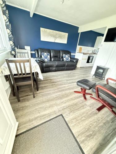 a living room with a black leather couch and chairs at East Coast Chalets 333 at California Sands Holiday Park, Dog Friendly in Great Yarmouth