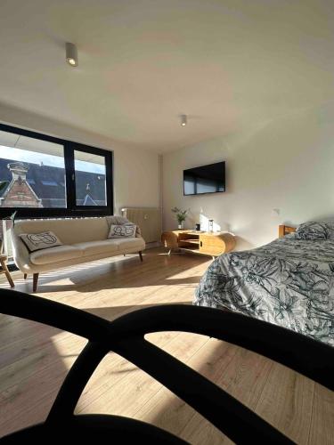 une chambre avec un lit et un salon avec un canapé dans l'établissement Studio cosy, à Armentières