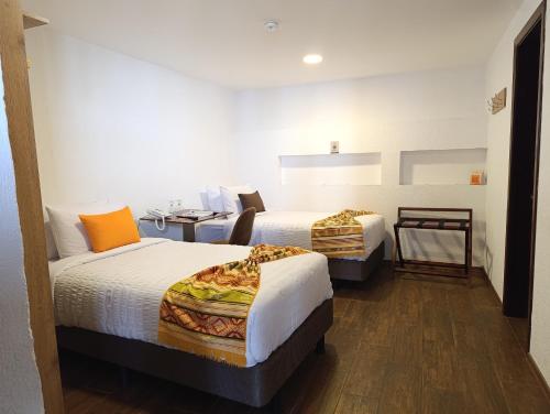 a hotel room with two beds and a desk at Casona Tobar Hotel in Quito