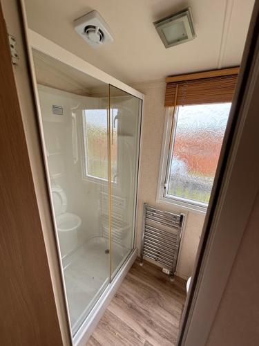y baño con ducha de cristal y ventana. en The Beach Hideaway Pet Friendly 2 Bedroom Static Caravan Clarach Bay, en Aberystwyth