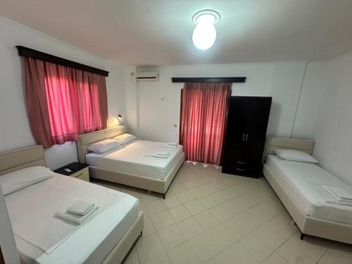 a hotel room with two beds and red curtains at Vila Reni Risi in Ksamil