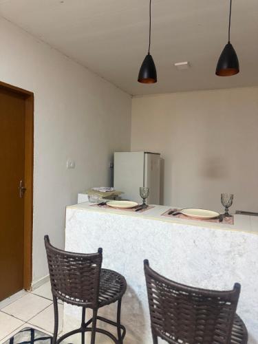 a kitchen with two chairs and a counter with plates on it at Flat mobiliado in Arapiraca