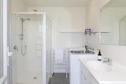 a white bathroom with a shower and a sink at Kereru's Nest in Rotorua