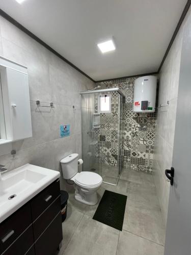 a bathroom with a shower and a toilet and a sink at Steves House Flat Hotel in Puerto Iguazú