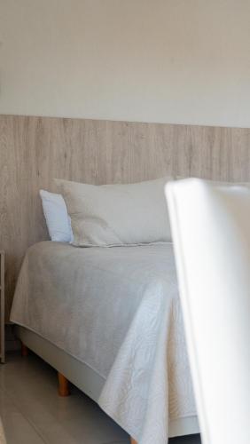 a bed with white sheets and pillows on it at Altair Hotel in San Clemente del Tuyú