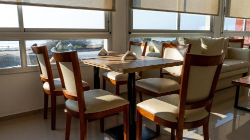 a dining room with a table and chairs and windows at Altair Hotel in San Clemente del Tuyú
