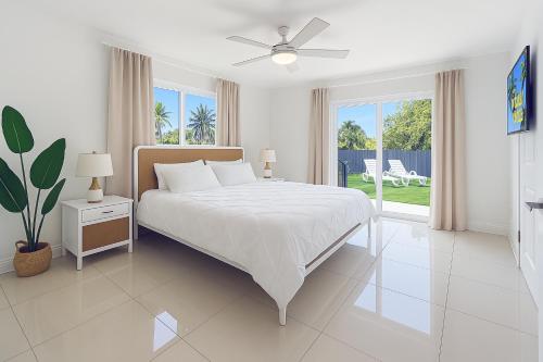 a white bedroom with a bed and a ceiling fan at Central Miami Oasis, Near Brickell, Grove & Little Havana in Miami