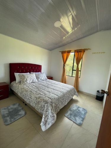 a bedroom with a bed with a red headboard and two windows at El Alpino Cabaña Glamping & Camping in Guatavita