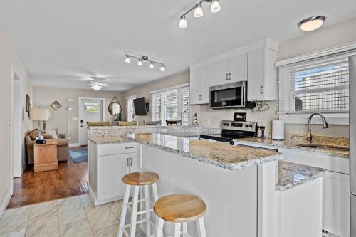 a kitchen with white cabinets and a bar with stools at Mi Faro Unit A Duplex in Harkers Island