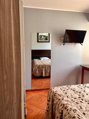 a room with a bedroom with a bed and a television at Hospedaje in Ayacucho