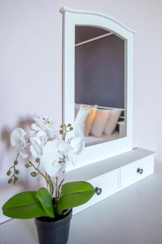 a white dresser with a mirror and a plant at Ionian Kaizer Boutique in Achílleion