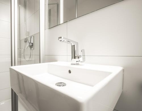 een witte badkamer met een wastafel en een spiegel bij Hotel-Restaurant Alpha in Friedrichshafen