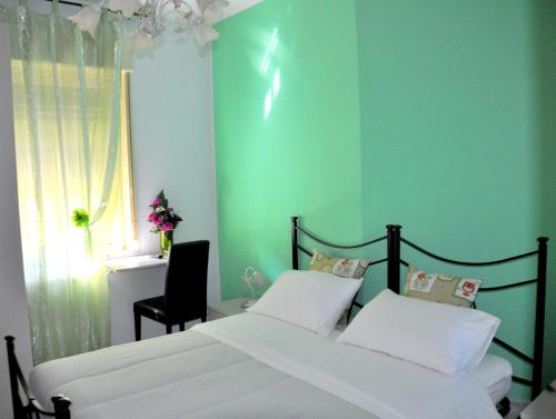 - une chambre verte avec un lit et une chaise dans l'établissement B&B Villa Angelica, à Mili Marina