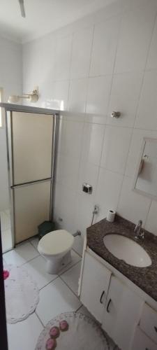 a white bathroom with a toilet and a sink at Apartamento Cedros- Excelente localização! in Corumbá