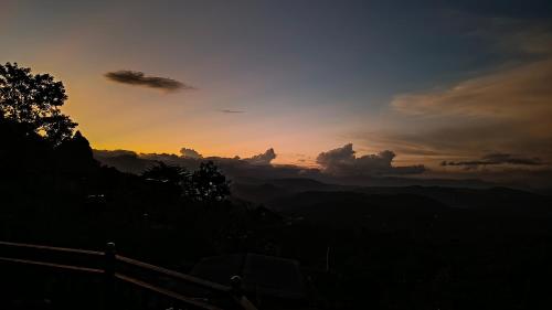 a sunset in the mountains with a fence in the foreground at Adisham village home in Haputale