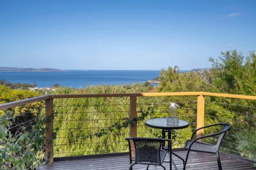 a table and two chairs on a deck with the ocean at Ocean Views 20kms from CBD Sleeps 10 in Kingston Beach