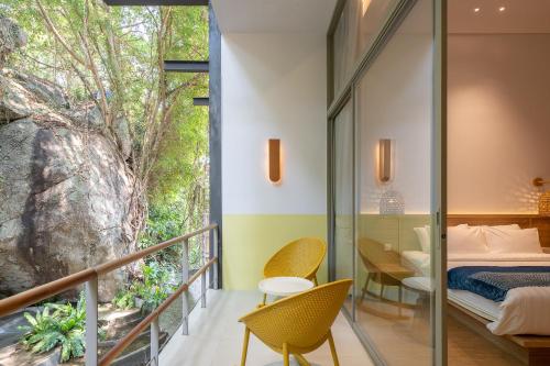 a bedroom with a balcony with a bed and chairs at Ozone Cave in Thong Nai Pan Noi