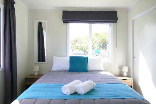 a bedroom with a blue bed with two white pillows at Riverside Whakatane Holiday Park in Whakatane