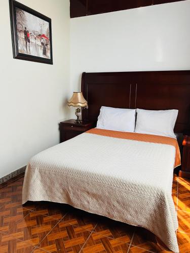 a bedroom with a large bed with a wooden floor at Hostería Casa Marquez in León