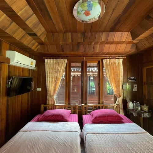 two beds in a room with wooden walls at Healing House Holistic Farm Stay in Ban Wet