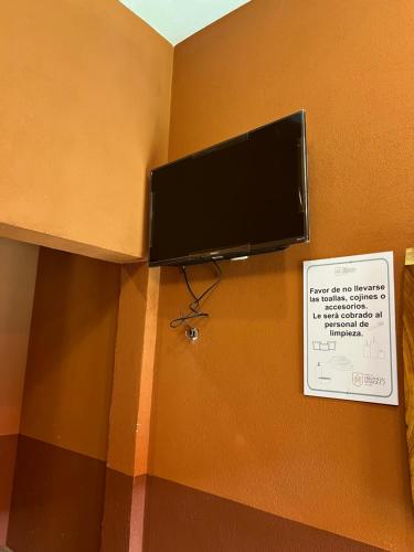 a flat screen tv hanging on a wall with a sign at Hostería Casa Marquez in León