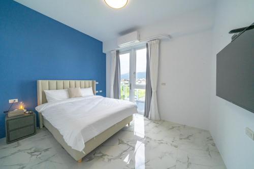 a blue bedroom with a bed and a window at 好室成雙House x Double in Toucheng