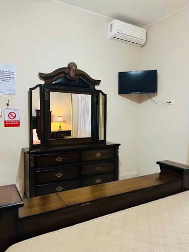 a bedroom with a dresser with a mirror and a tv at Hostería Casa Marquez in León